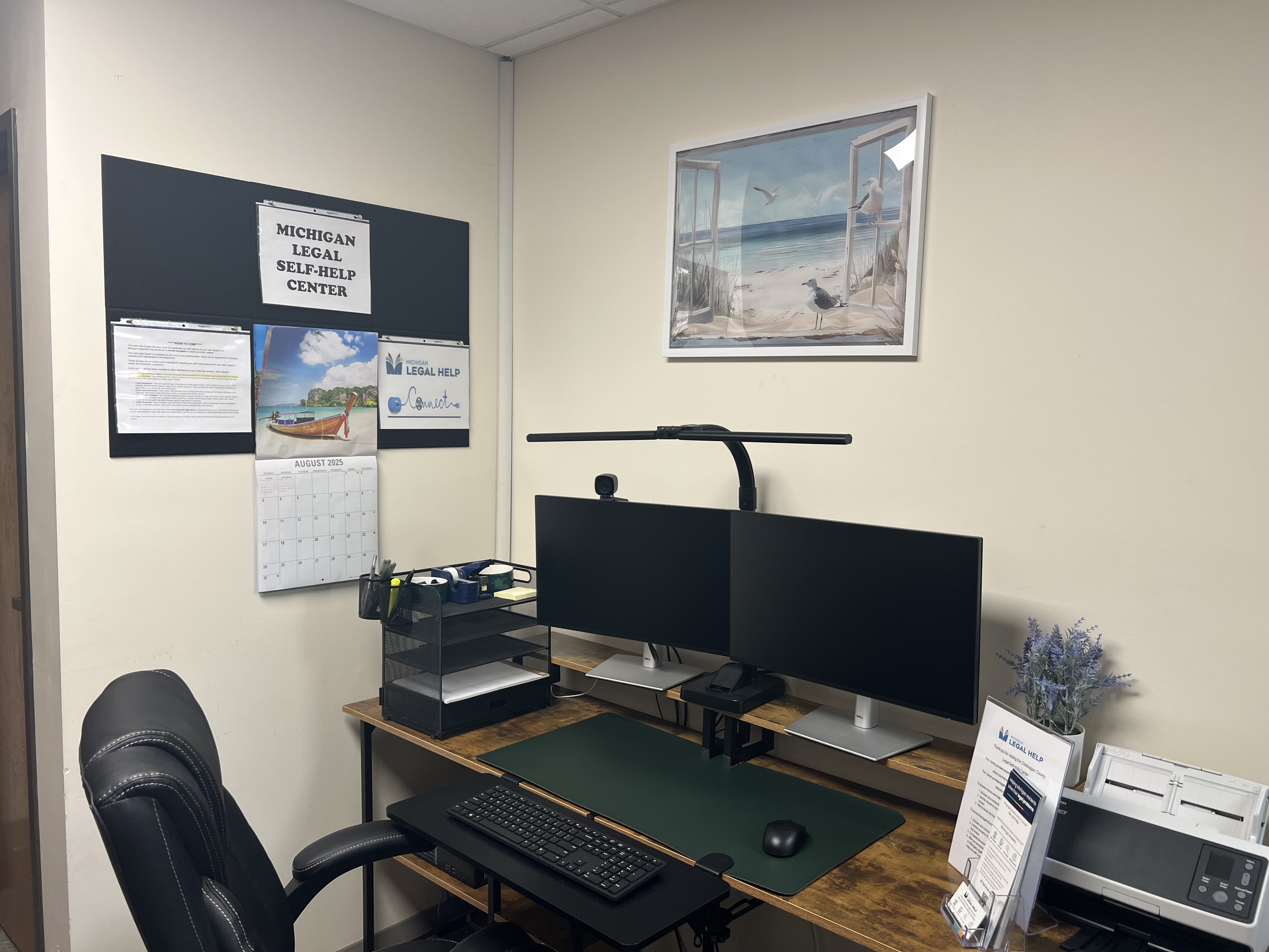 The inside of a legal Self Help Center showing a double monitor computer, comfortable chair, and printer